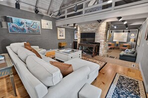 A spacious living room with a white sofa, a fireplace, and artwork on the walls. - Artist's Cottage | Eclectic Retreat Near Coligny (Hilton Head Island)