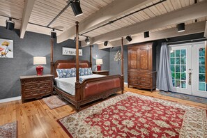 A bedroom with a four-poster bed, wooden nightstands, a large wardrobe, and a red floral rug. - Artist's Cottage | Eclectic Retreat Near Coligny (Hilton Head Island)