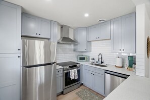 Una cocina moderna con electrodomésticos de acero inoxidable, armarios blancos y salpicadero de azulejos.