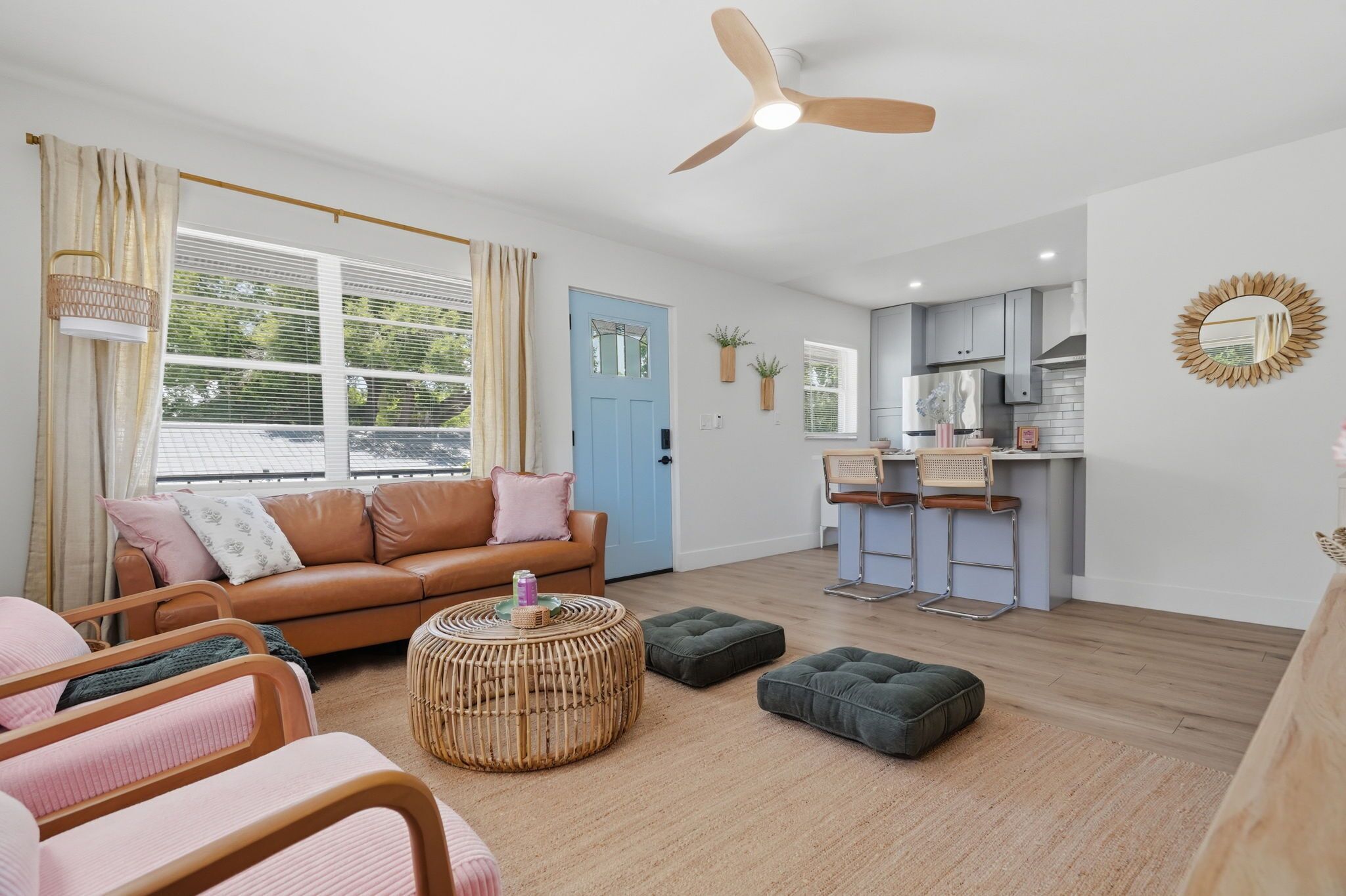 A living room with a sofa, ottomans, a round coffee table, and a ceiling fan.