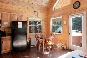 Ein Holzblockhaus-Interieur mit Essbereich, Küche und einer Tür, die nach draußen führt.