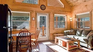 Ein Holzblockhaus-Interieur mit Essbereich, einer Couch und einem Tisch.