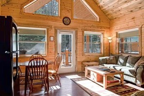 Ein Holzblockhaus-Interieur mit Essbereich, einer Couch und einem Tisch.