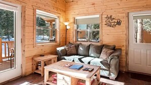 Ein Holzblockhaus-Innenraum mit einer Couch, einem Tisch und einer Lampe.