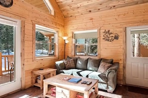 Ein Holzblockhaus-Innenraum mit einer Couch, einem Tisch und einer Lampe.