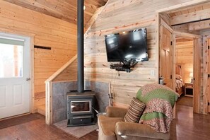 Et hyggeligt værelse med pejs, et fjernsyn monteret på væggen og et blødt siddeområde.