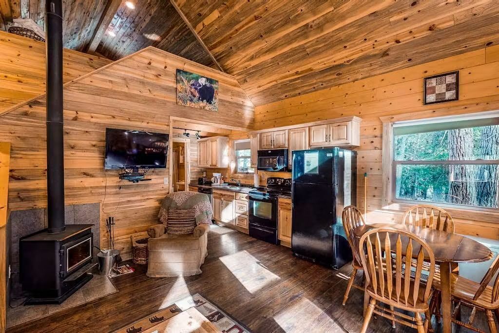 L’intérieur d’un chalet en bois comprend une cuisine, un coin repas et une cheminée.