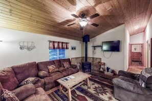 A cozy living room with a wooden ceiling, a sofa set, a coffee table, a television, and a fireplace. - Eldora Cabin | Hot Tub on the Rio Grande! (South Fork)