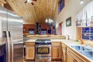 Une cuisine avec des meubles de rangement en bois, un réfrigérateur en acier inoxydable, une cuisinière et un évier.
