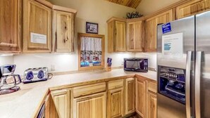 A kitchen with wooden cabinets, a stainless steel refrigerator, a microwave, and a toaster. - Gressoney Family Retreat | Pond & Hot Tub (South Fork)