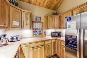 A kitchen with wooden cabinets, a stainless steel refrigerator, a microwave, and a toaster. - Gressoney Family Retreat | Pond & Hot Tub (South Fork)
