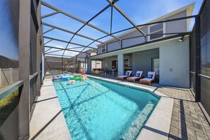 Una piscina interior con agua cristalina, rodeada de sillas de descanso y una zona de estar cubierta.