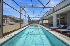 A swimming pool with a covered area, lounge chairs, and a view of the surrounding buildings. - Hogwarts & Star Wars Themed Rooms, Pool, Game Room (Davenport)