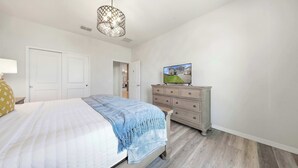Ett sovrum med en säng, en byrå och en tv som visar ett hus.