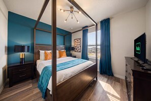 A modern bedroom with a four-poster bed, a nightstand with a lamp, a dresser, and a television displaying the Hulu logo. - Hogwarts & Star Wars Themed Rooms, Pool, Game Room (Davenport)