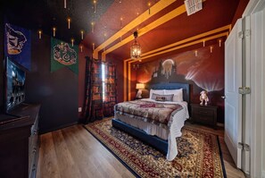 Un dormitorio con una cama grande, una mesita de noche, una estantería y una pared decorada con un mural de un castillo.