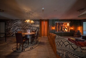 A cozy living room with a stone wall mural, a round dining table, and a sofa. - Hogwarts & Star Wars Themed Rooms, Pool, Game Room (Davenport)
