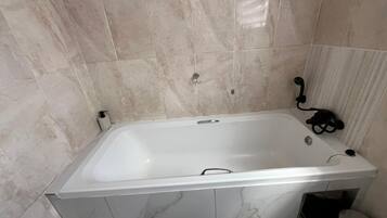 Une salle de bain avec une baignoire blanche, des toilettes et un espace douche.