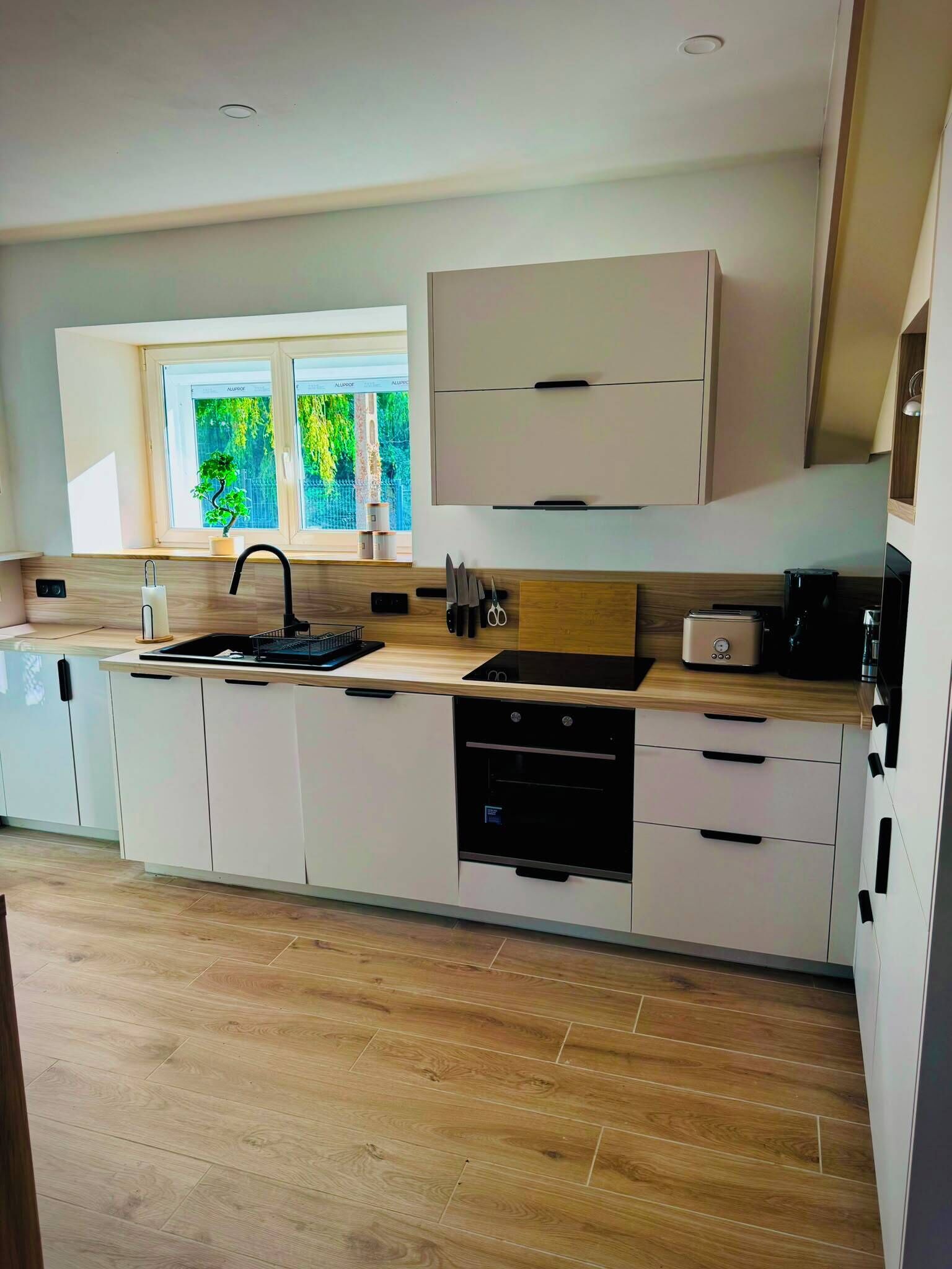 Een moderne keuken met een inbouwvaatwasser, een spoelbak en een raam met uitzicht op groen.