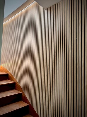 A staircase with wooden steps leading up to a wall with vertical wooden slats. - The Breton Getaway (Plourivo)