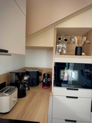 A compact kitchen with a microwave, toaster, coffee maker, and a coffee pot. - The Breton Getaway (Plourivo)