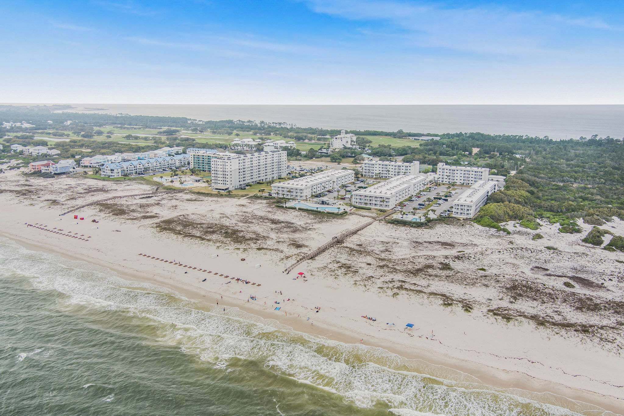 Ein Küstenhotel mit mehreren Gebäuden, einem Strand und einem Steg.