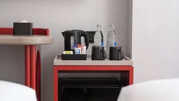 Eine Küchenzeile mit einer Kaffeemaschine, einem Wasserkocher, einer Wasserflasche und einer Tasse auf einer Arbeitsfläche.