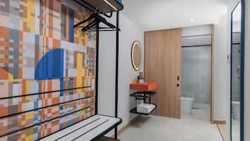 Ein modernes Badezimmer mit gefliestem Boden, einer Holztür, einem Spiegel und einem Waschbecken mit roter Schale.