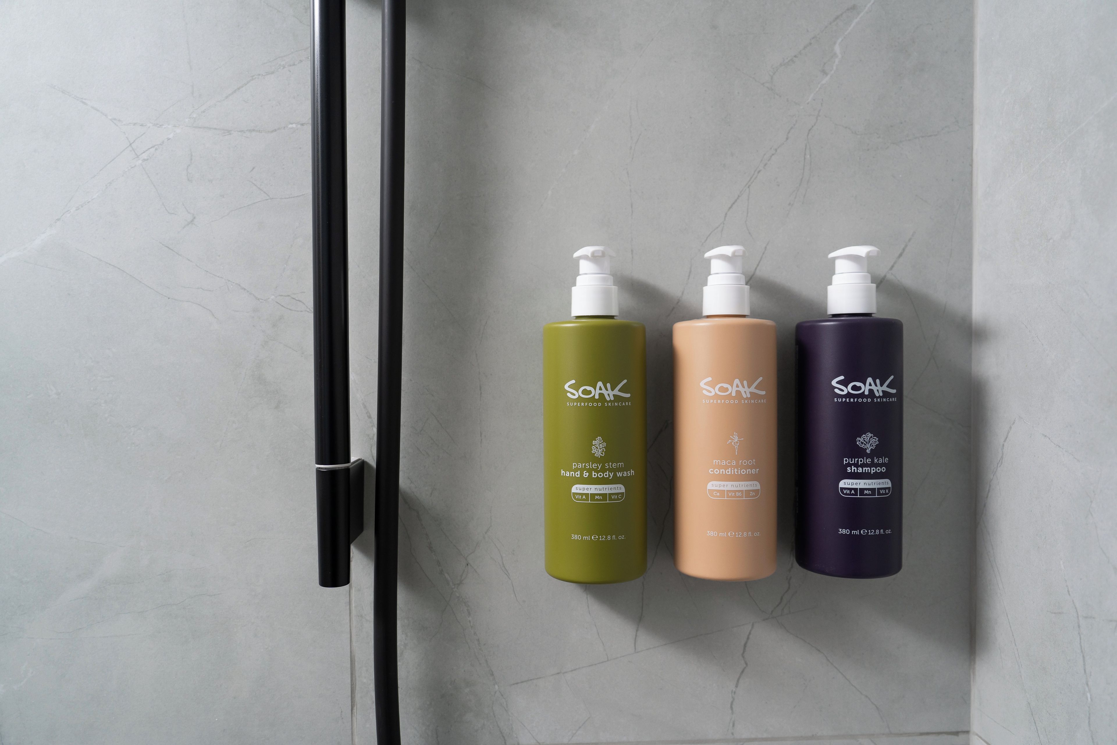 Trois bouteilles de produits de soins de la peau de la gamme Soak Superfood, posées sur une surface en marbre.