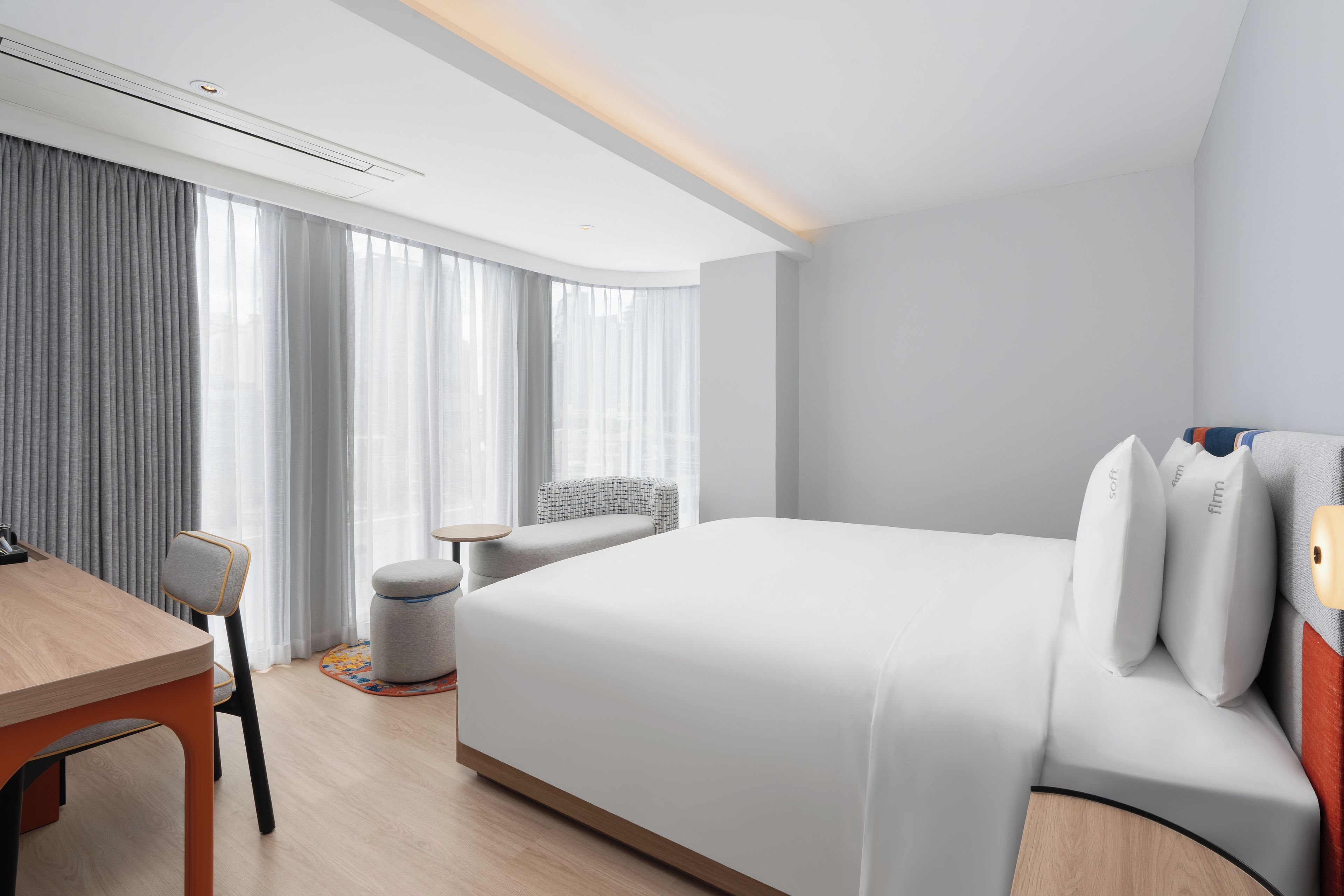 A modern hotel room with a large bed, a desk, and a chair.