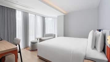 A modern hotel room with a large bed, a desk, and a chair.