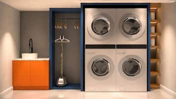 Une buanderie moderne équipée d’un lave-linge et d’un sèche-linge encastrés, d’un évier et d’un étendoir.