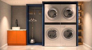 Une buanderie moderne équipée d’un lave-linge et d’un sèche-linge encastrés, d’un évier et d’un étendoir.