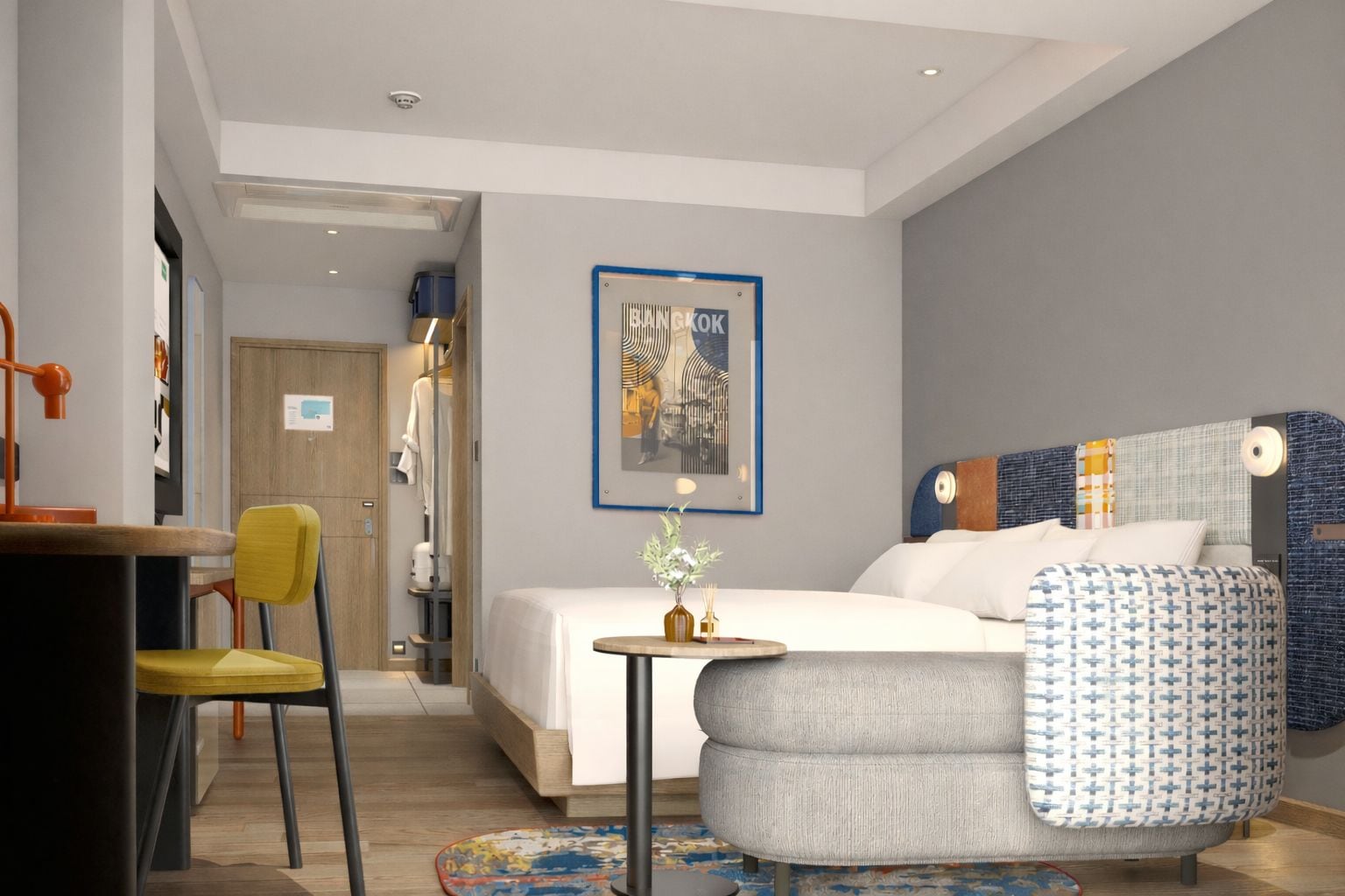 A modern hotel room with a bed, a desk, a chair, and a small table with a vase.