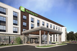A Holiday Inn hotel with a modern design, featuring a covered entrance and a landscaped area with a bench. - Holiday Inn Gulfport Biloxi Beach by IHG (Gulfport)