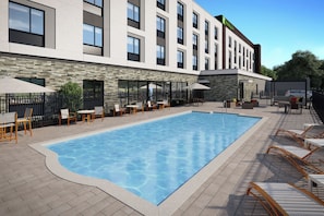 A hotel with a swimming pool, outdoor seating, and a stone facade. - Holiday Inn Gulfport Biloxi Beach by IHG (Gulfport)
