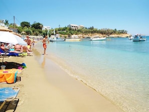 A beach with clear water, umbrellas, and boats. - Apollonia apartments- Cozy apartment next to the beach with sea view (Agia Pelagia)