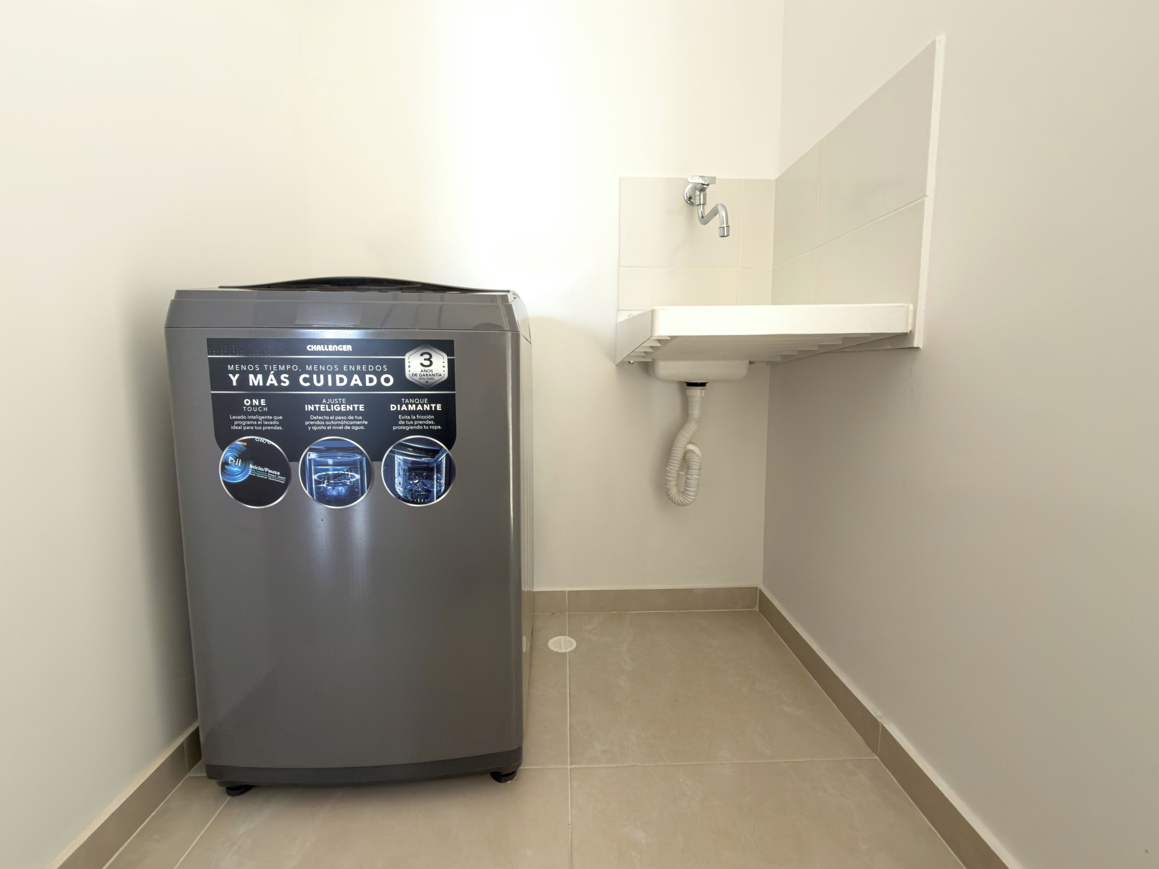 A compact, gray, wall-mounted washing machine with a control panel featuring a touch screen and three circular indicators.