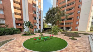 Un patio con un sube y baja, edificios de ladrillo y follaje.
