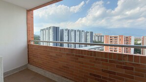 Un balcón con vista despejada a edificios altos y un cielo azul con nubes.