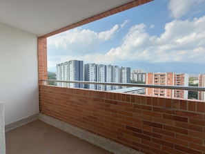 A balcony with a clear view of high-rise buildings and a blue sky with clouds.