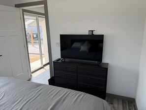Un dormitori amb un llit, una televisió damunt d'una petita taula i una porta corredissa de vidre que dona a una zona exterior.