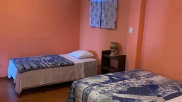 Un dormitorio con dos camas, una mesita de noche y una ventana con cortinas.