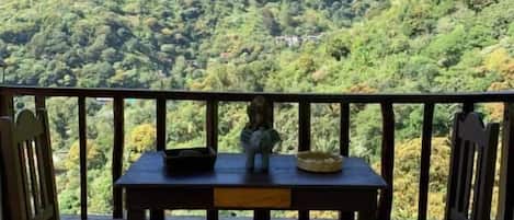 Un balcon avec une table et des chaises donnant sur un paysage montagneux.