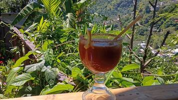 A glass of beverage on a wooden railing with a mountainous landscape in the background.