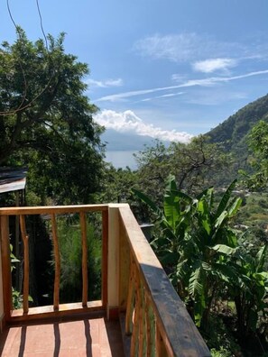 Un balcón de madera con vistas a un paisaje montañoso y un cuerpo de agua.