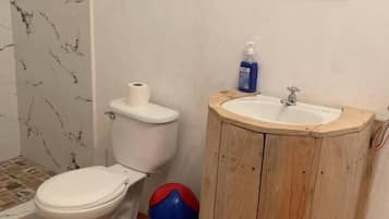 Un baño con inodoro, lavamanos y zona de ducha.