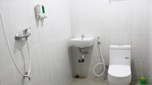 Une salle de bain avec des toilettes, un lavabo et une douche.