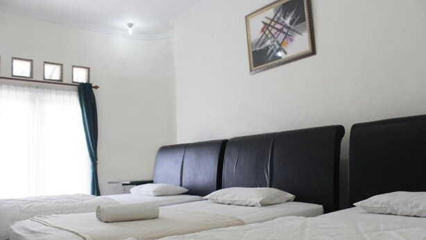 Une chambre d’hôtel avec deux lits, une grande fenêtre avec des rideaux et un tableau encadré au mur.
