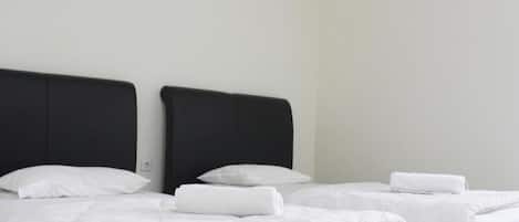 Habitación de hotel con dos camas, cada una con ropa de cama blanca y cabeceros negros.